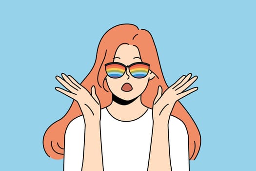 Woman with rainbow glasses exclaims loudly and makes gesture of surprise when sees unusual phenomenon or hears exciting news. Shocked girl in sunglasses with rainbow stripes looks at screen