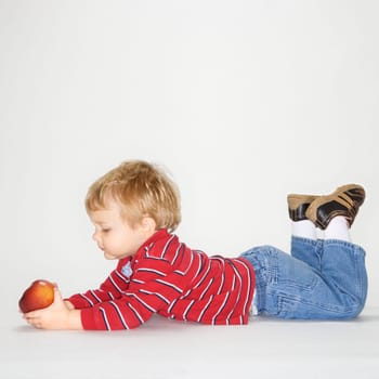 Studio portrait of Caucasian boy holding apple against white background.