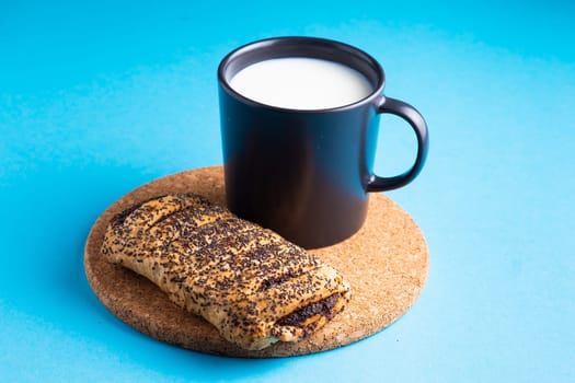 Breakfast bread and cup of milk on yellow and blue background