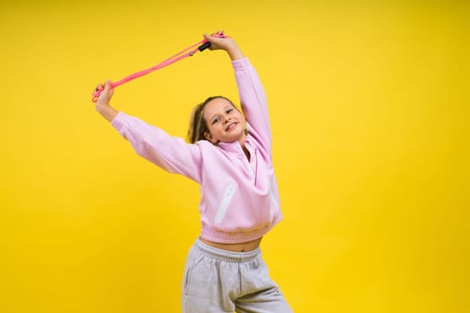 Beautiful sportsgirl with skipping rope isolated on a yellow studio