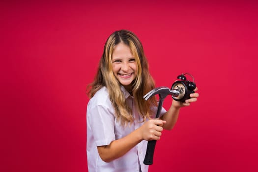 Kid girl holding hammer and alarm clock smiling with happy and cool smile on face. showing teeth.