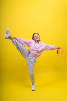 Beautiful sportsgirl with skipping rope isolated on a yellow studio
