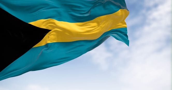 Close-up view of the Bahamas national flag waving in the wind. Black triangle on hoist, aquamarine-gold-aquamarine horizontal bands. 3d render illustration. Rippled fabric.