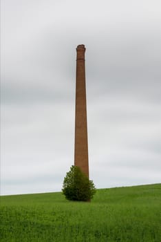 A lonely chimney and a stove in the middle of a field.