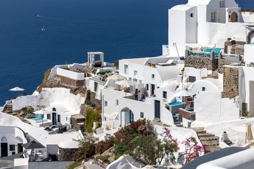 Oia, Santorini, Greece - July 3, 2021: Whitewashed houses with terraces and pools and a beautiful view in Oia on Santorini island, Greece