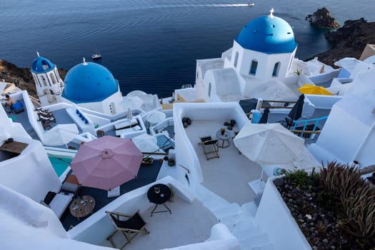Oia, Santorini, Greece - June 28, 2021: View from viewpoint of Oia village with blue dome of  greek orthodox Christian church and traditional whitewashed greek architecture.  Santorini, Greece