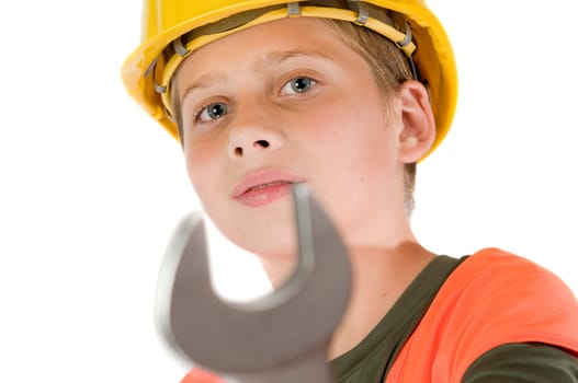 Head and shoulders view of a young teenage boy wearing a yellow hardhat showing a spanner at the camera with shallow depth of field isolated on white.
