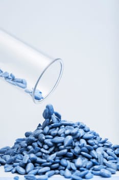 Studio shot of sunflower seeds falling out of glass tubes against white background blau getönt.