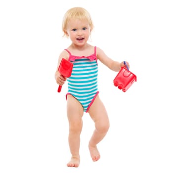 Baby girl in swimsuit holding bucket and shovel