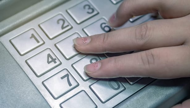 Woman's hand is pressing numbers on keypad to enter verification code in financial transaction.