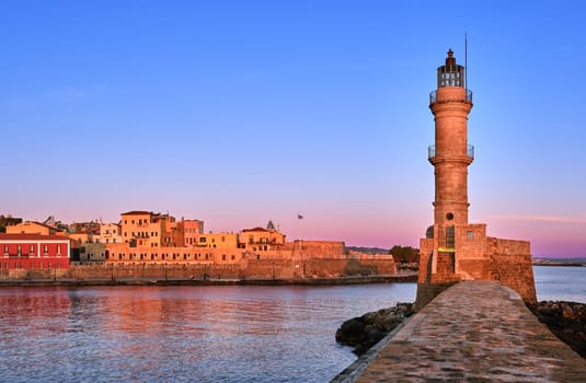 Egyptian Lighthouse of Old Venetian harbour of Chania, Crete, Greece at sunrise. Soft sky colors from blue to pink, Firka castle walls and Maritime museum of Crete in background.