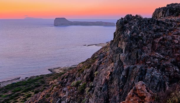 Sunset view of Gramvousa islet behind the rocky hills of Balos beach area, Crete, Greece. Rich colors of sundown and diagonal composition. Selective focus
