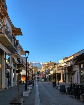 Typical street of Chania, Crete, Greece with shops, cafes and restaurants for evening promenade. No tourists in early morning. Great view of Cretan mountains and peaks covered with snow.