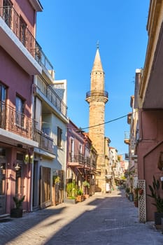 Early morning in old narrow streets of Chania, Crete, Greece and historical monument of Ottoman era - Ahmet aga minaret. Bright sunlight, summer.