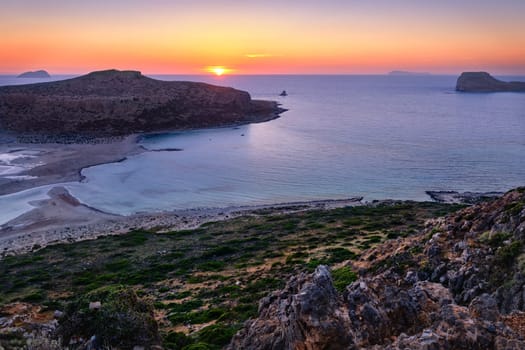 Beautiful sunset view of Cape Tigani and Gramvousa islet from Balos beach, Crete, Greece. Sundown and rich colors of rocky slopes and greenery.