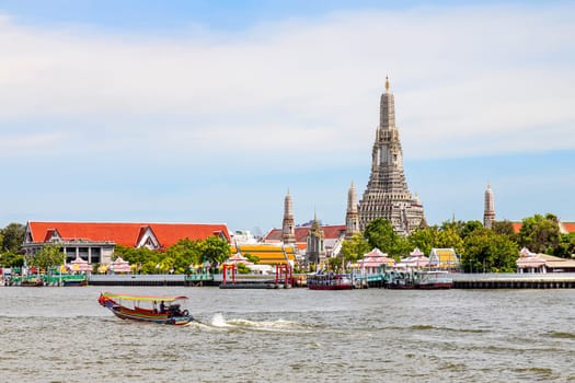 Bangkok Thailand - June 28, 2023 A long-tailed boat is sailing on the Chao Phraya River. It's a quick water journey in Bangkok and tourists also get to see the Wat Arun (Temple of Dawn) riverside.