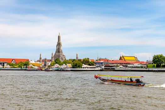 Bangkok Thailand - June 28, 2023 A long-tailed boat is sailing on the Chao Phraya River. It's a quick water journey in Bangkok and tourists also get to see the Wat Arun (Temple of Dawn) riverside.