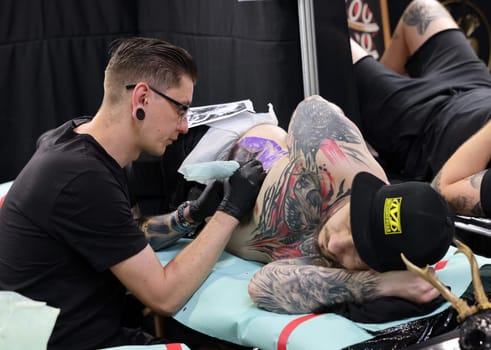 Krakow, Poland -  June 12, 2022: Unidentified  participant at 15th Tattoofest Convention in Cracow. One of the most prestigious tattoo festivals. Tattoo artist at work.