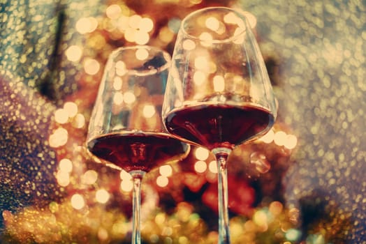 Two glass of red wine in front of christmas tree lights bokeh. New year eve and xmas celebration party. Luxury romantic holiday dinner.