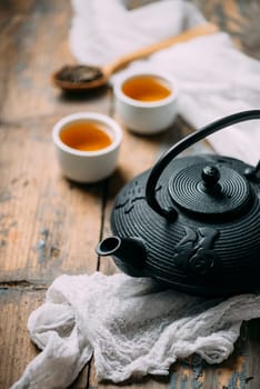 Traditional japanese herbal tea recipe prepared in cast iron teapot with organic dry herbs. Alternative medicine. Healthy asian green tea in tea pot on vintage wooden table background.