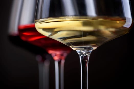 Three glass of red, rose and white wine over black background. Wine card menu design. Closeup of wineglasses with luxury wines for wine tasting.