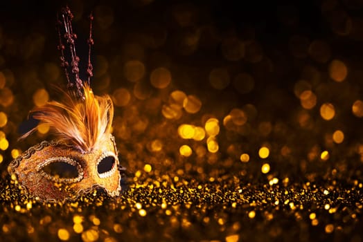 Luxury venetian mask on dark godlen bokeh background. New year and christmas party celebration design banner. Carnival masquerade fantasy costume ball.