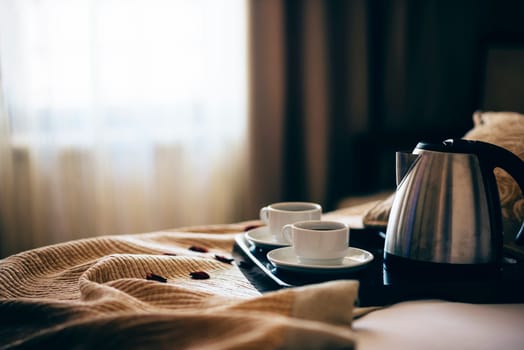 Morning breakfast with black coffee in bedroom. Two cups of coffee on bed decorated with rose petals in luxury hotel bedroom.