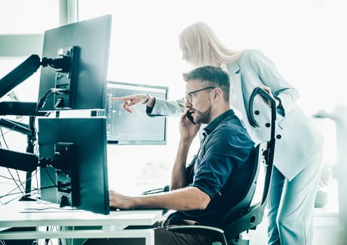 Stock broker business team trading online watching charts and data analyses on multiple computer screens in modern corporate work station office