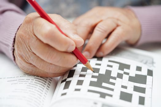 Asian elderly woman playing sudoku puzzle game to practice brain training for dementia prevention, Alzheimer disease.
