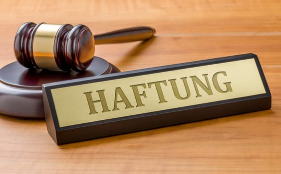 A gavel and a name plate with the engraving Liability in german - Haftung.
