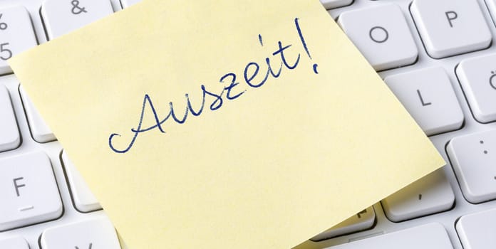 Sticky note on a keyboard - Time out in german - Auszeit