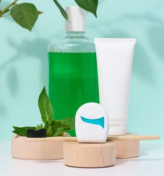 Refreshing mouthwash in a transparent plastic bottle and dental floss, white tube on a blue background