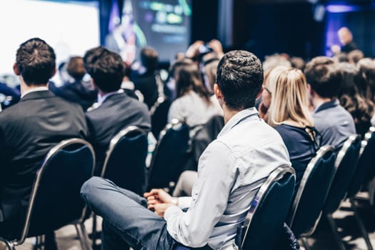 Speaker giving a talk in conference hall at business event. Rear view of unrecognizable people in audience at the conference hall. Business and entrepreneurship concept