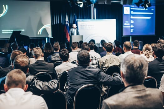 Speaker giving a talk in conference hall at business event. Rear view of unrecognizable people in audience at the conference hall. Business and entrepreneurship concept
