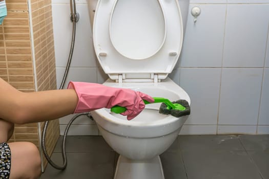 Woman cleaning toilet ware that is very dirty.