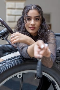 Attractive girl is handing the keys of a modern car. Focused on the girl. Vertically.