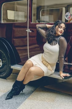 Attractive girl is relaxing  on a vintage car.  Edited as a vintage photo. Vertically.