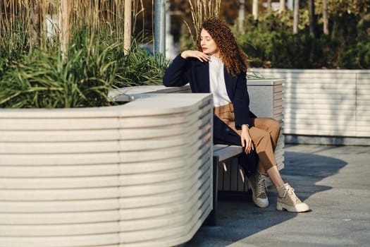 Pensive young woman sitting on a bench in the city