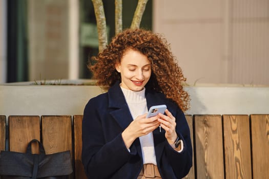 Smiling cute woman with smartphone outdoors
