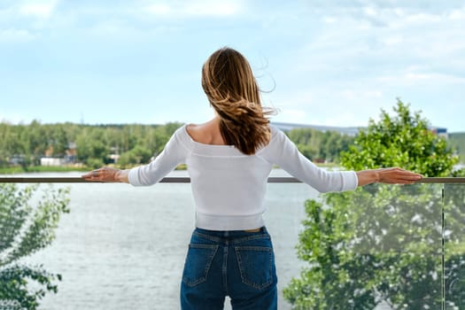 Unrecognizable woman enjoys the view of lake from observation desk, back view