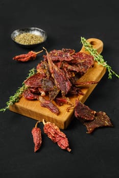 Spicy dried lamb jerky slices on black background