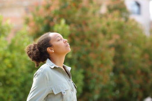 Profile of black woman meditating breathing fresh air in a park
