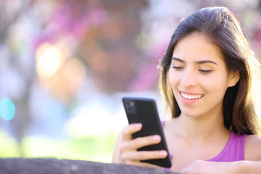 Happy woman using smart phone in a beautiful violet park