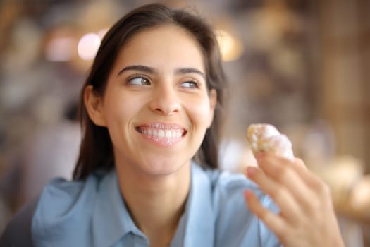Happy restaurant customer eating croissant with dirty lips looking away