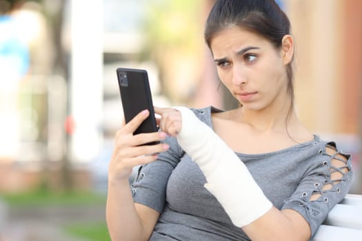 Suspicious convalescent girl checking phone content in the street