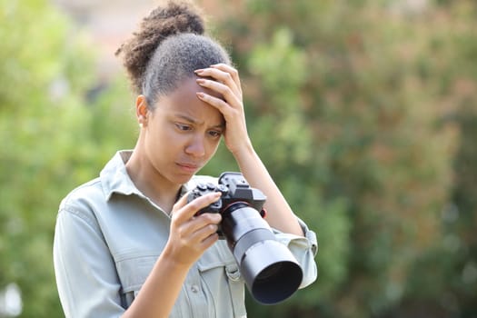 Black photographer complaining checking photos on camera in a park
