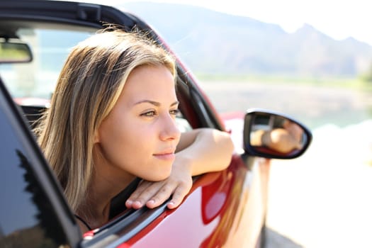 Beautiful car driver looking away in nature