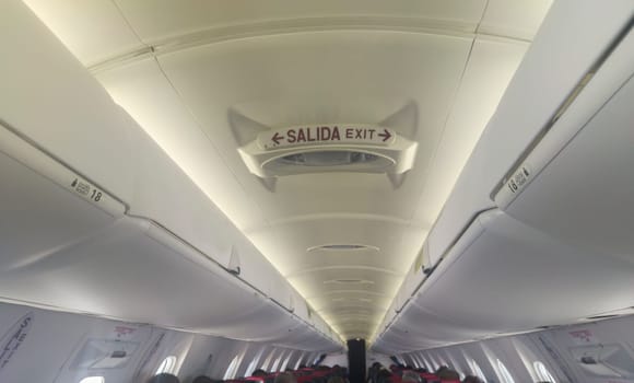 Non smoking and belt sign in aircraft cabin ceiling. Passenger jet airliner corridor