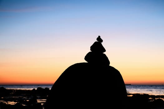 Stone pyramid on the Baltic Sea with a view of the sea at sunset and blue hour. Stones as silhouette. Spiritual view. Landscape shot from Poel island