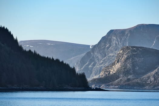 Fjord with mountains on horizon. Water glistens in the sun in Norway. Landscape photo from the north